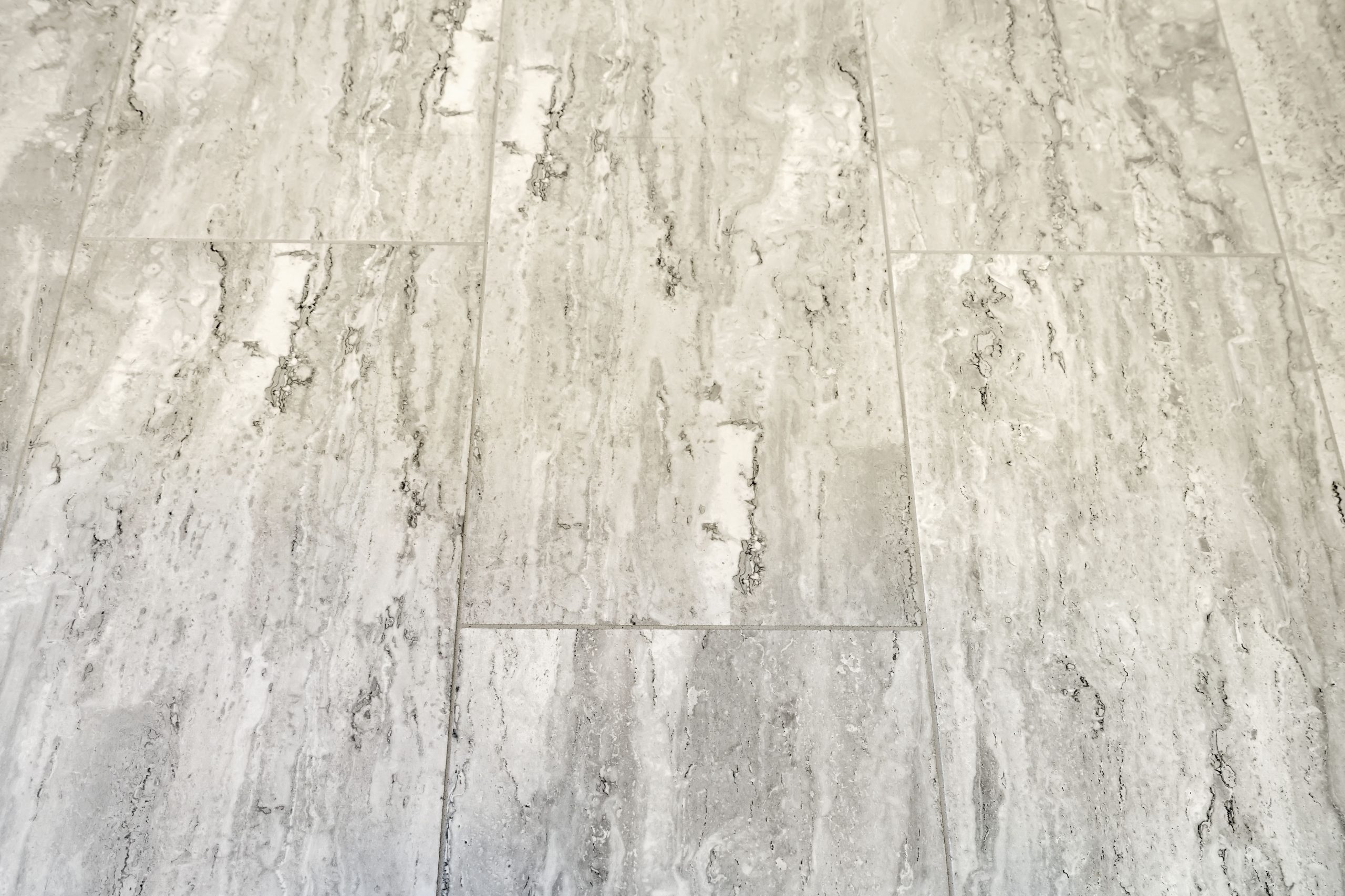 Gray and white stone tiles arranged in a staggered pattern, featuring a natural, textured surface with streaks and marbled veins.