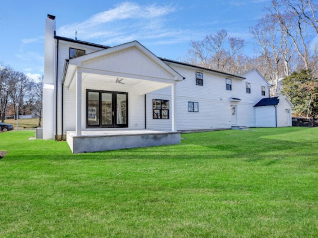 Outdoor living space with a custom covered porch and patio attached to a modern white home, designed for comfort and entertaining.