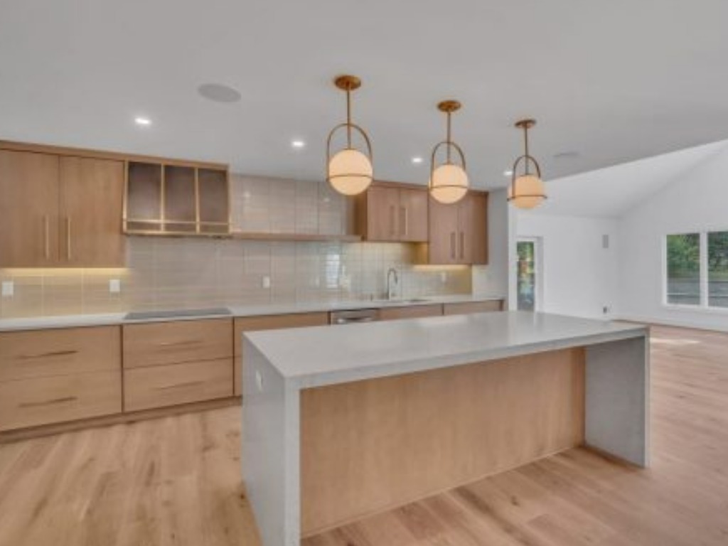 Modern kitchen designed through a design build process featuring wood cabinetry, large island, and pendant lighting in a custom New Jersey home.